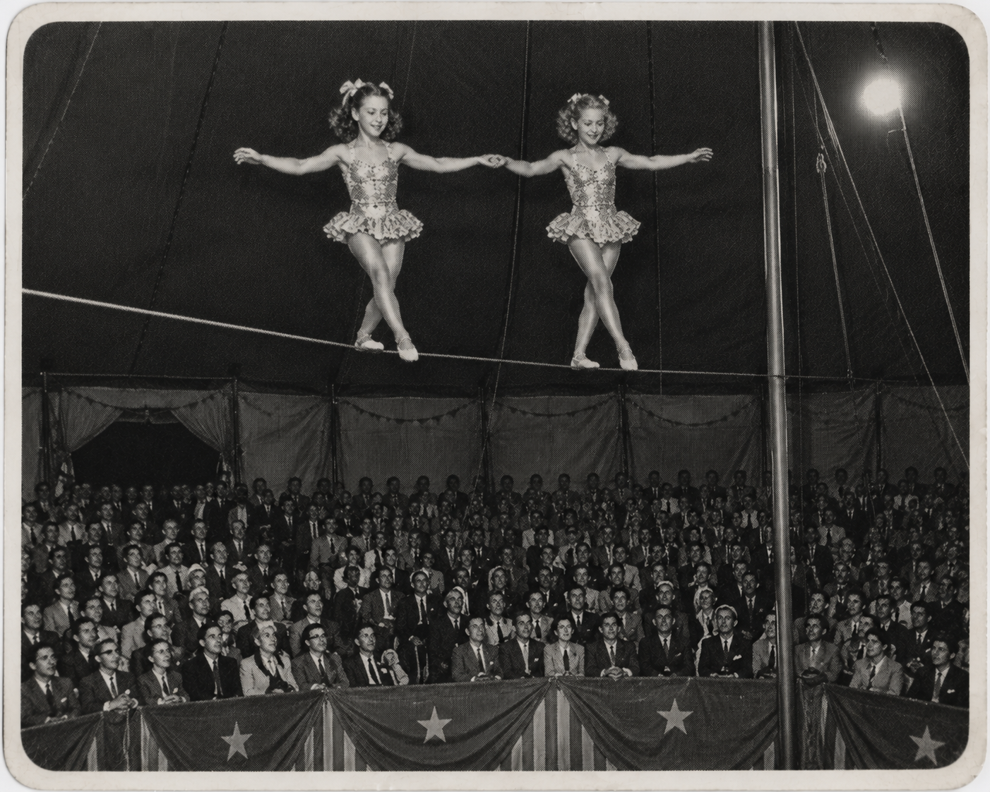 Archival newspaper photograph of the Marchetti twins performing on a tightrope above a circus ring.